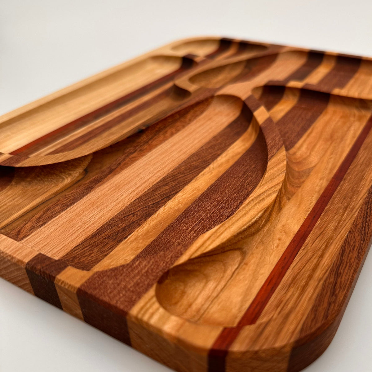 Wooden cutting board with a spoon and fork cutouts on a white background