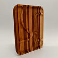 Wooden cutting board with embedded knife and fork on a light gray background