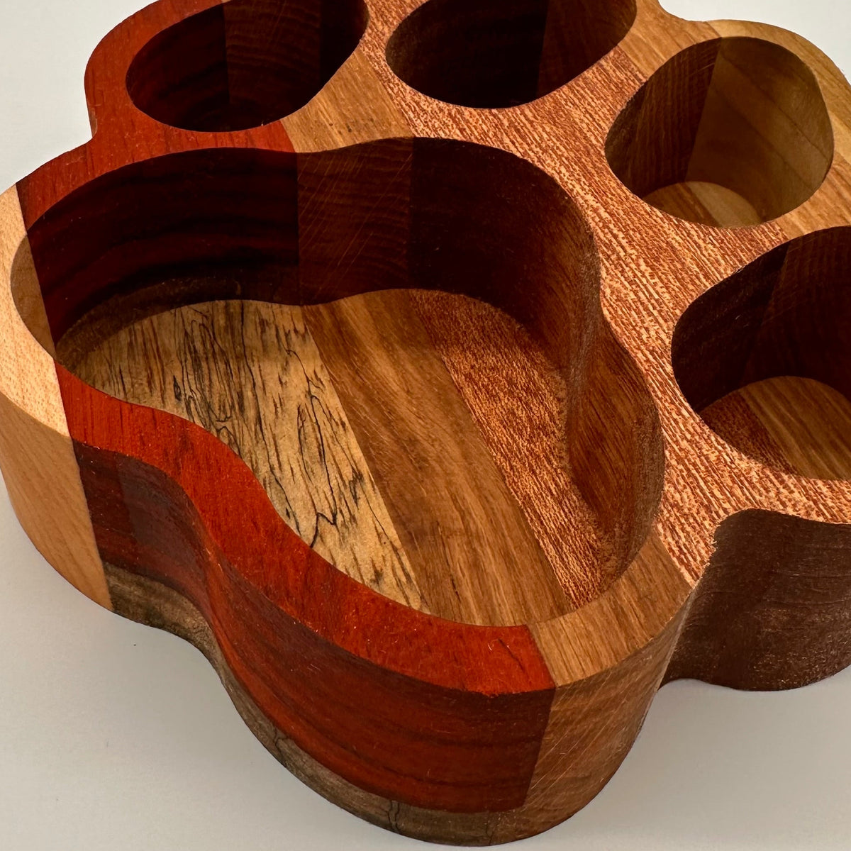 Wooden paw-shaped holder with multiple compartments on a light background