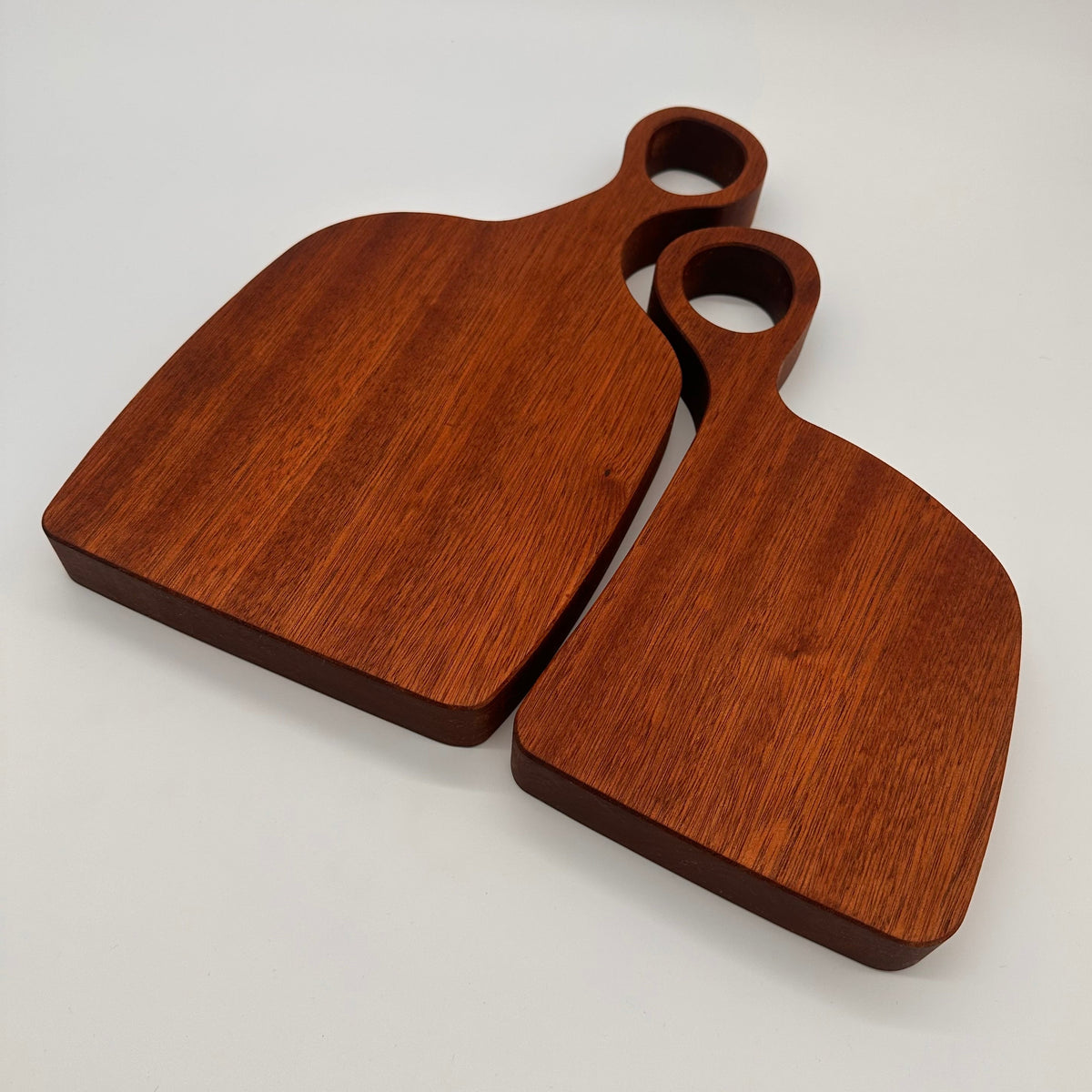 Two wooden cutting boards with handles on a light gray background