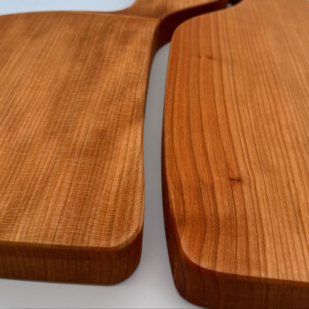 Two wooden cutting boards with handles on a light blue background