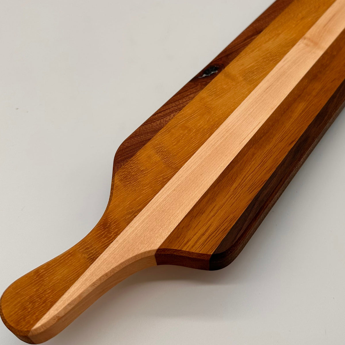 Wooden paddle with a striped design on a light gray background
