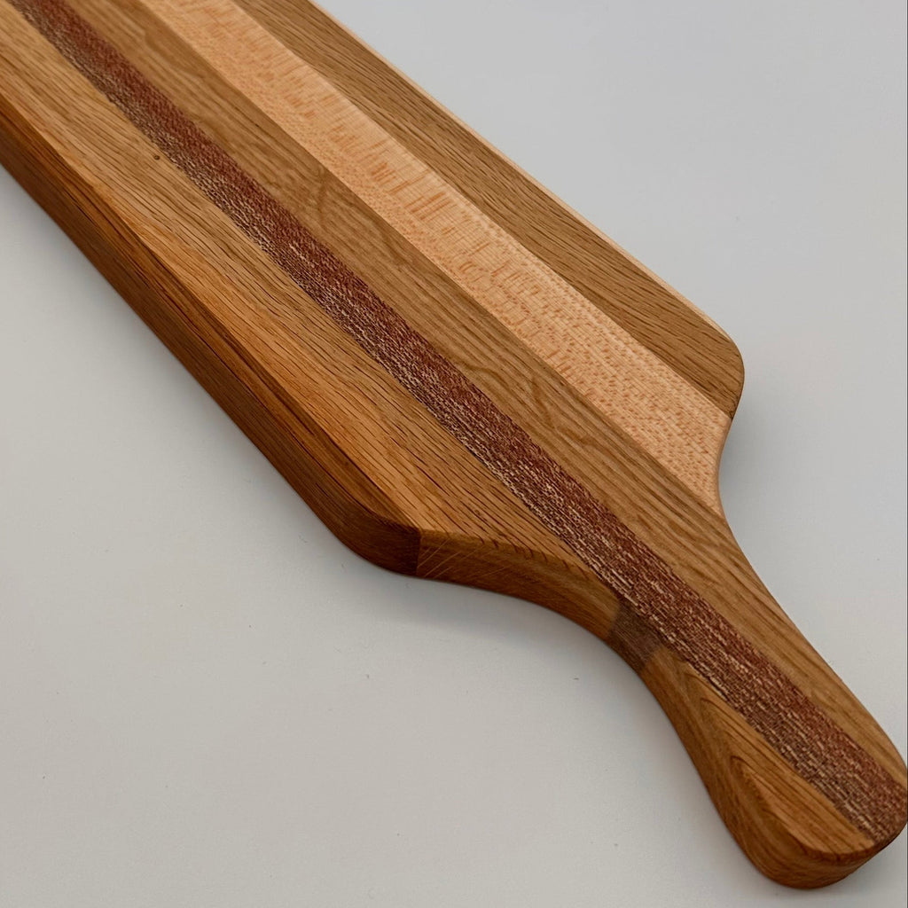Wooden cutting board with a handle on a light gray background
