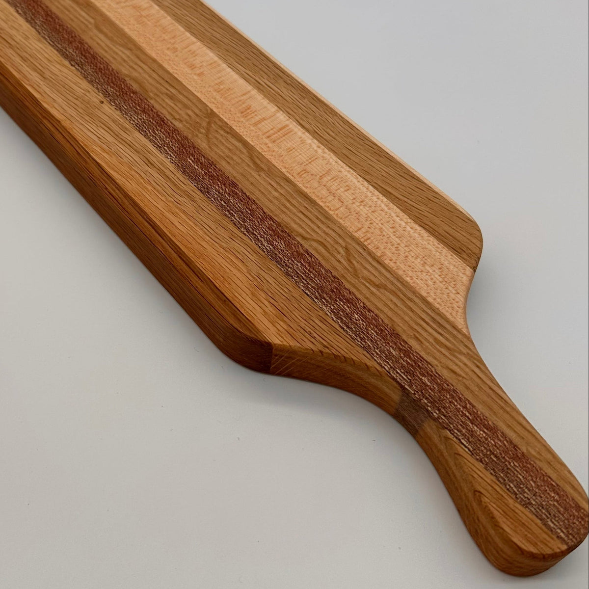 Wooden cutting board with a handle on a light gray background