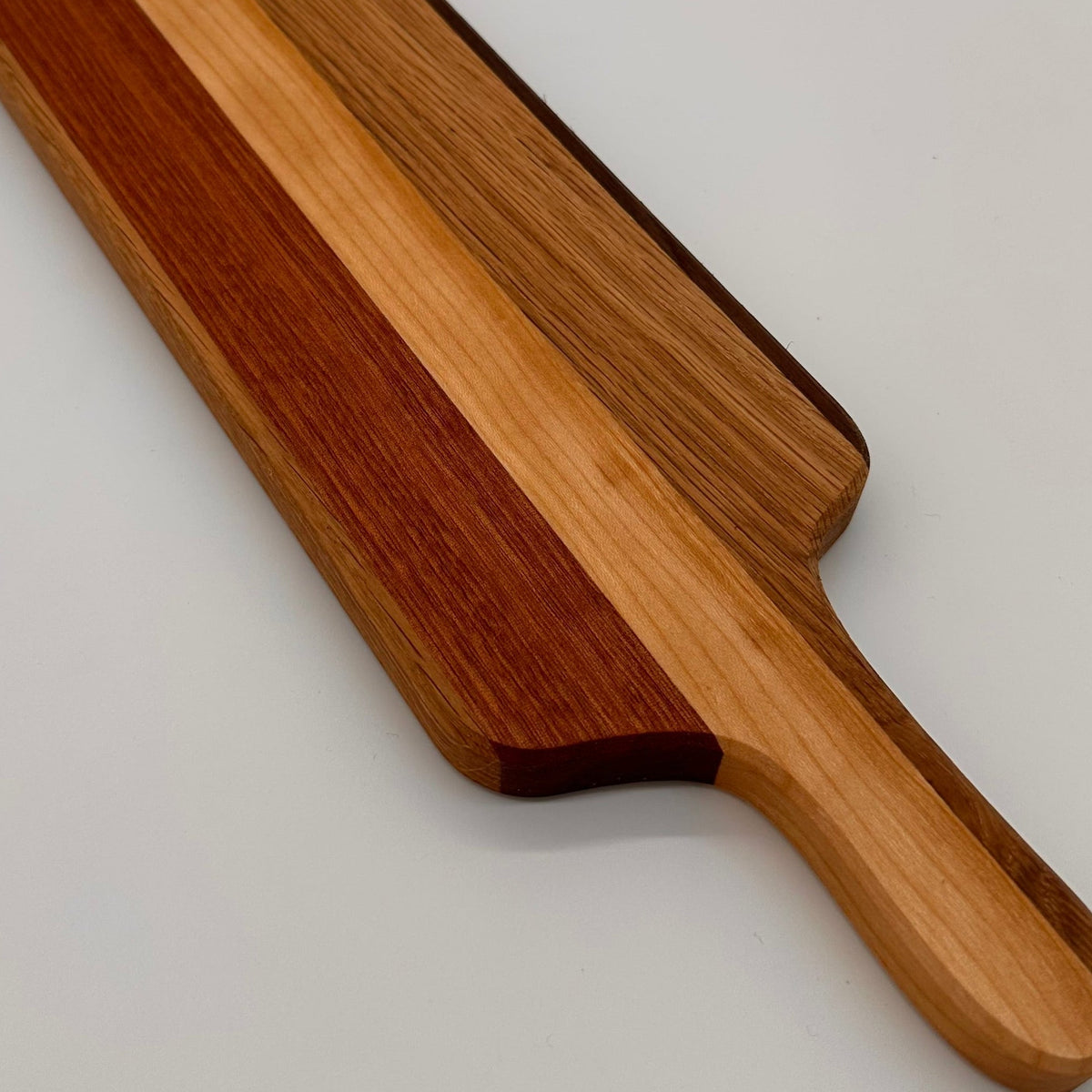 Wooden cutting board with a handle on a light gray background