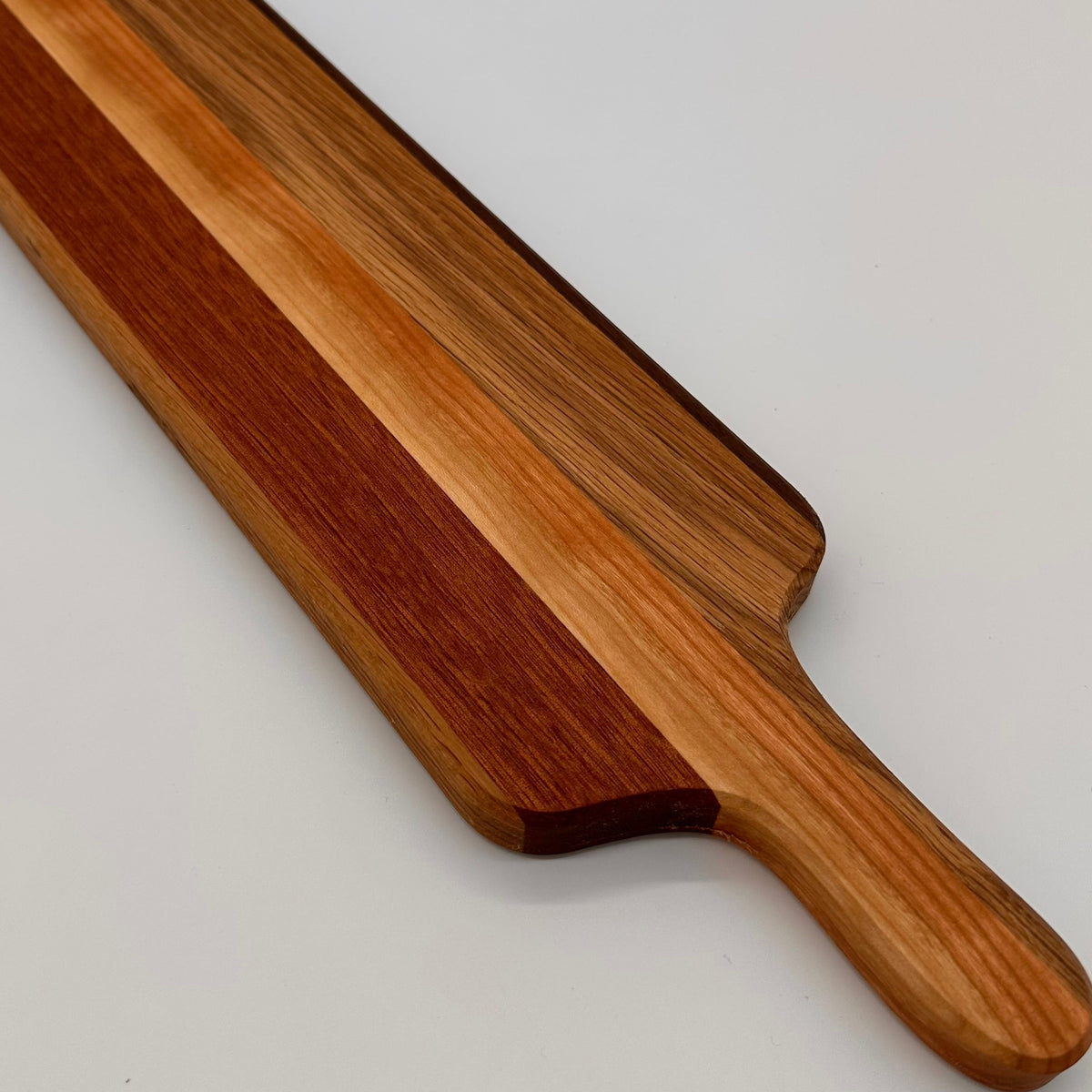 Wooden cutting board with a handle on a light gray background