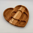 Wooden heart-shaped tray with compartments on a light gray background
