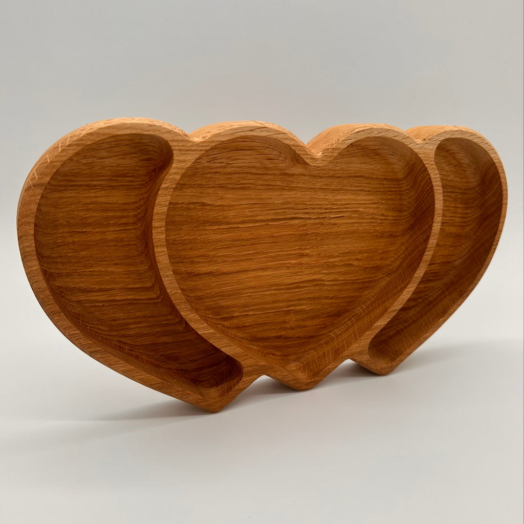 Three wooden heart-shaped bowls on a light gray background