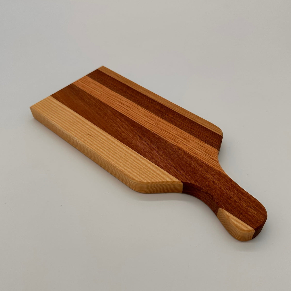 Wooden cutting board with a handle on a light gray background