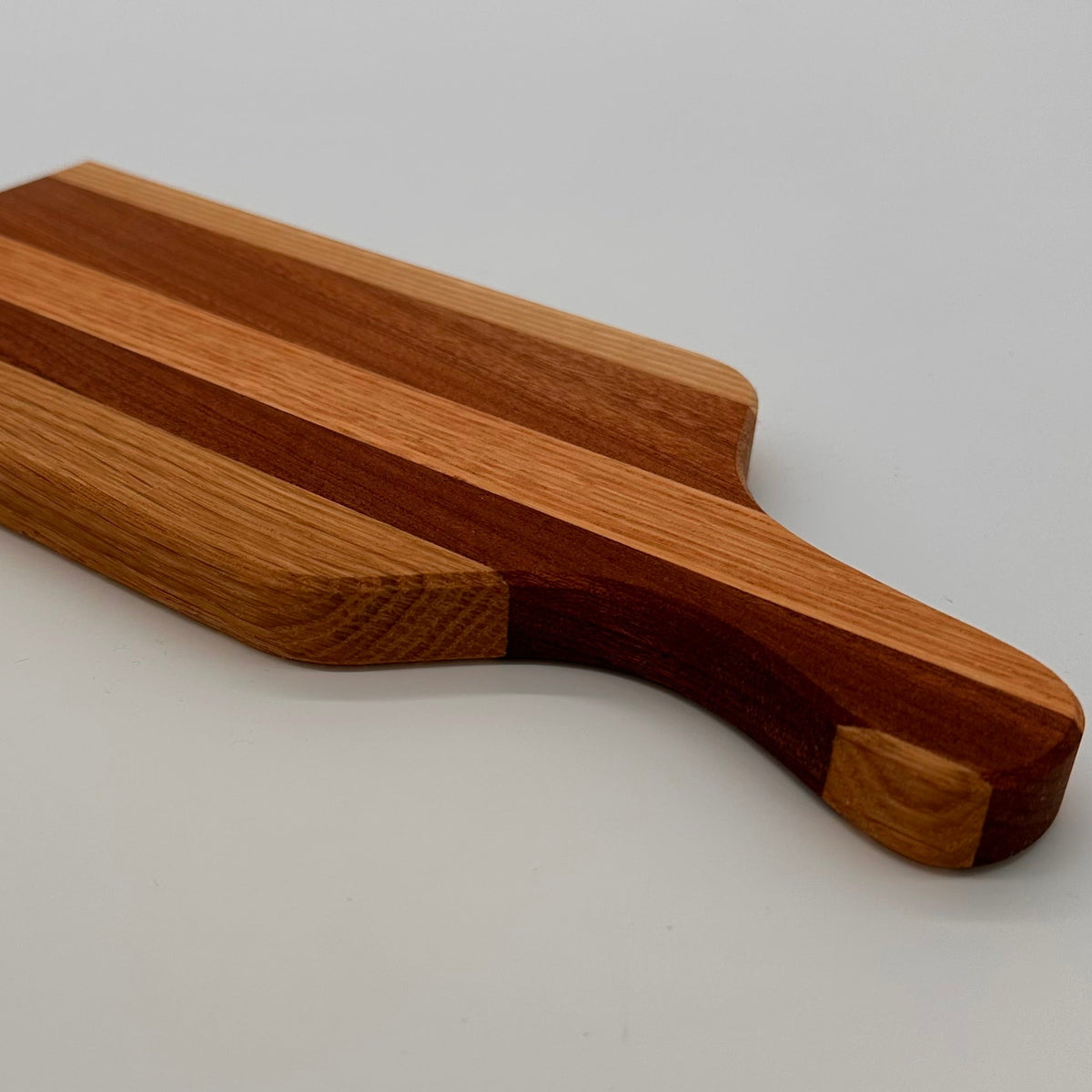 Wooden cutting board with a handle on a light gray background