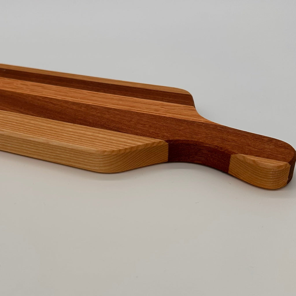 Wooden cutting board with a handle on a light gray background