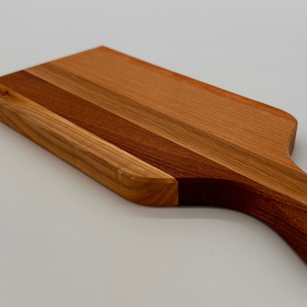 Wooden cutting board with handle on a light gray background