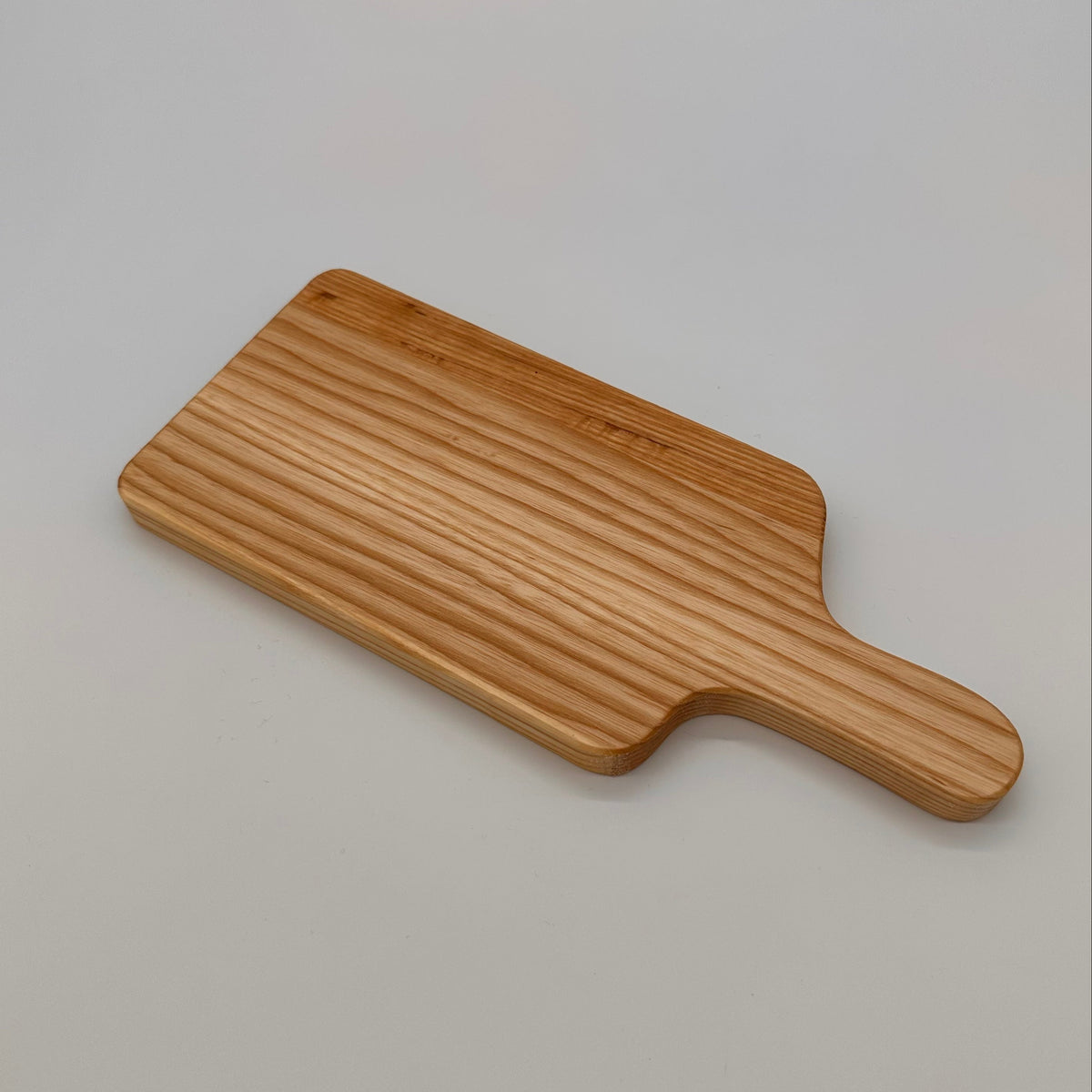 Wooden paddle cutting board on a light gray background