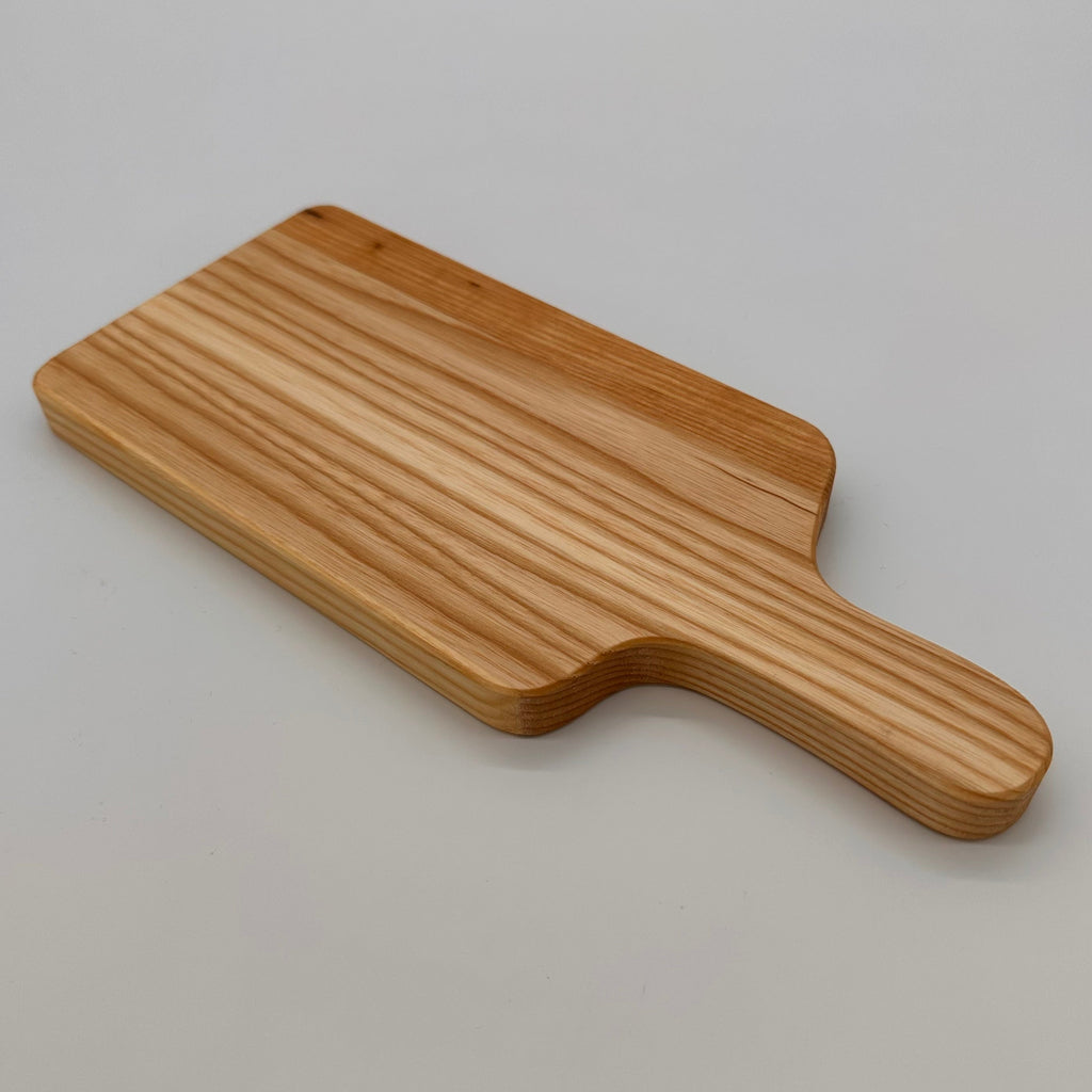 Wooden paddle cutting board on a light gray background
