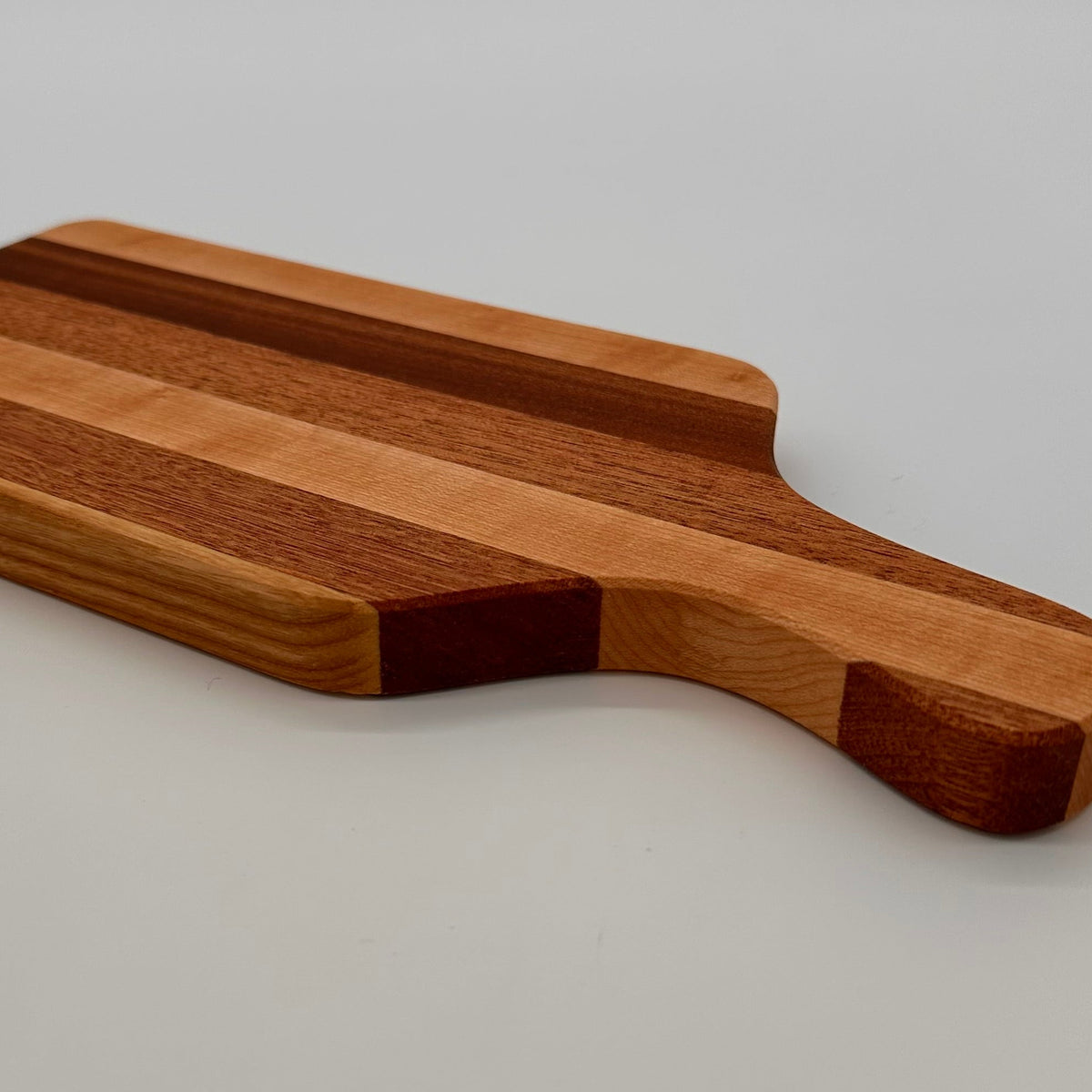 Wooden cutting board with a handle on a light gray background