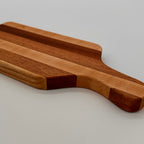 Wooden cutting board with a handle on a light gray background