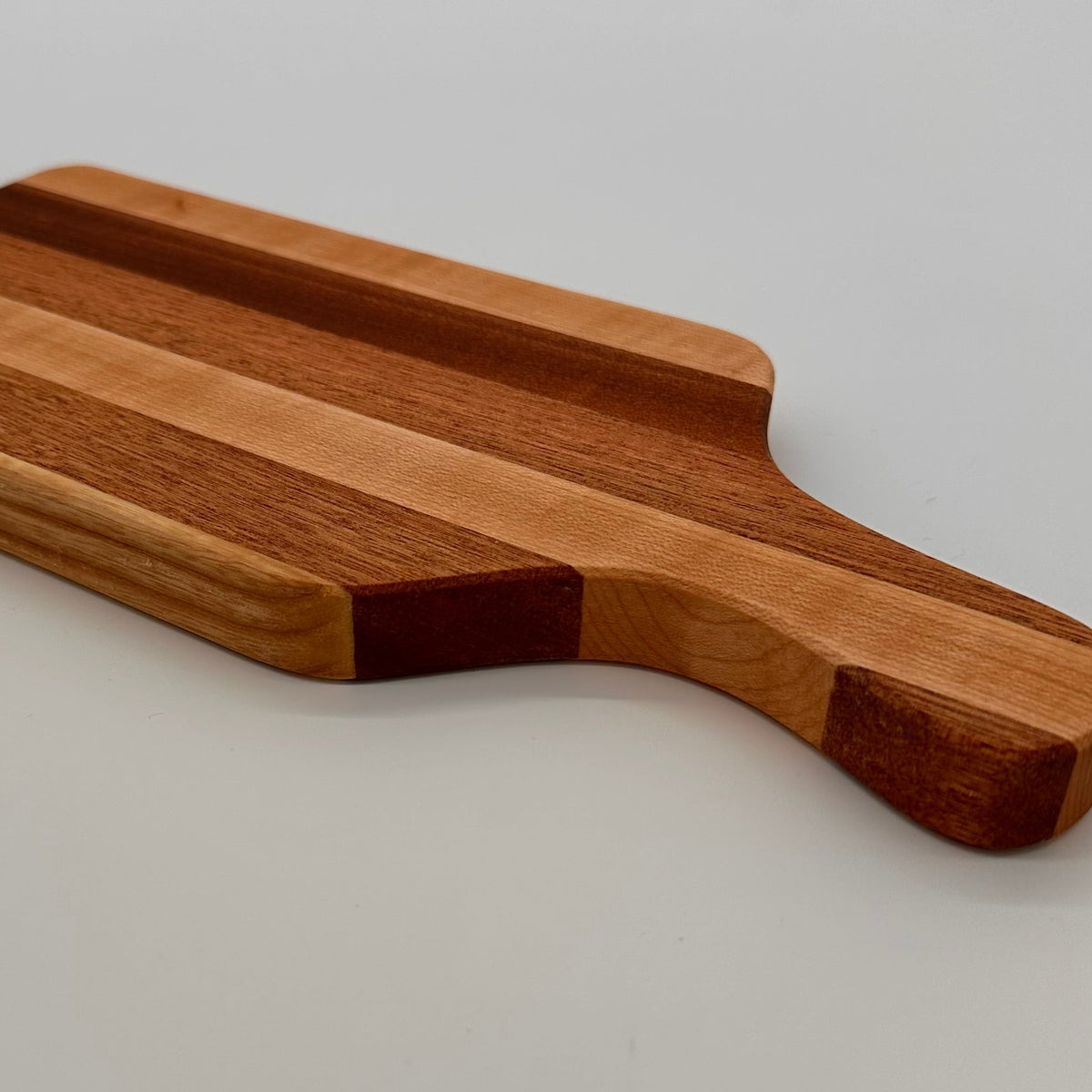 Wooden cutting board with a handle on a light gray background