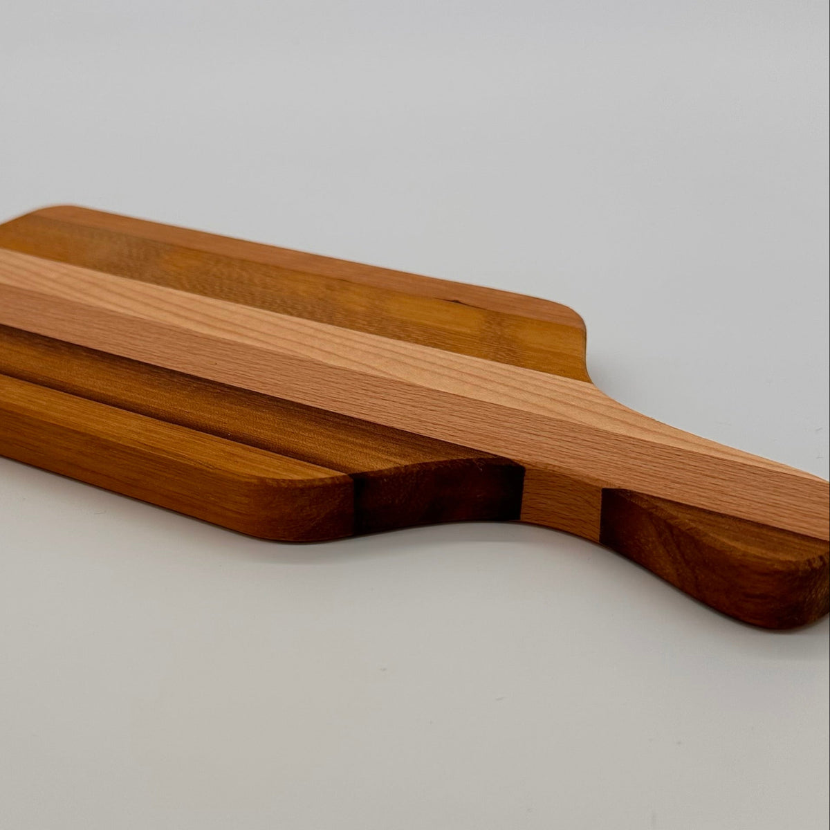 Wooden cutting board with handle on a light gray background
