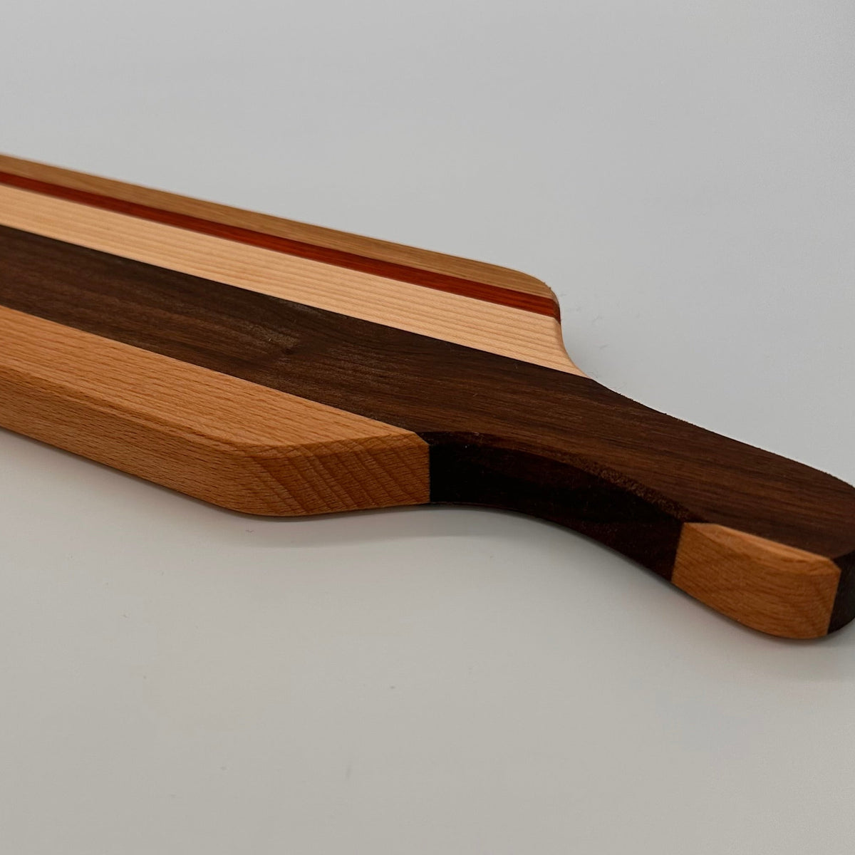 Wooden cutting board with a handle on a light gray background