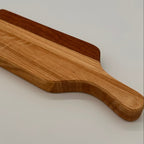 Wooden cutting board with a handle on a light gray background