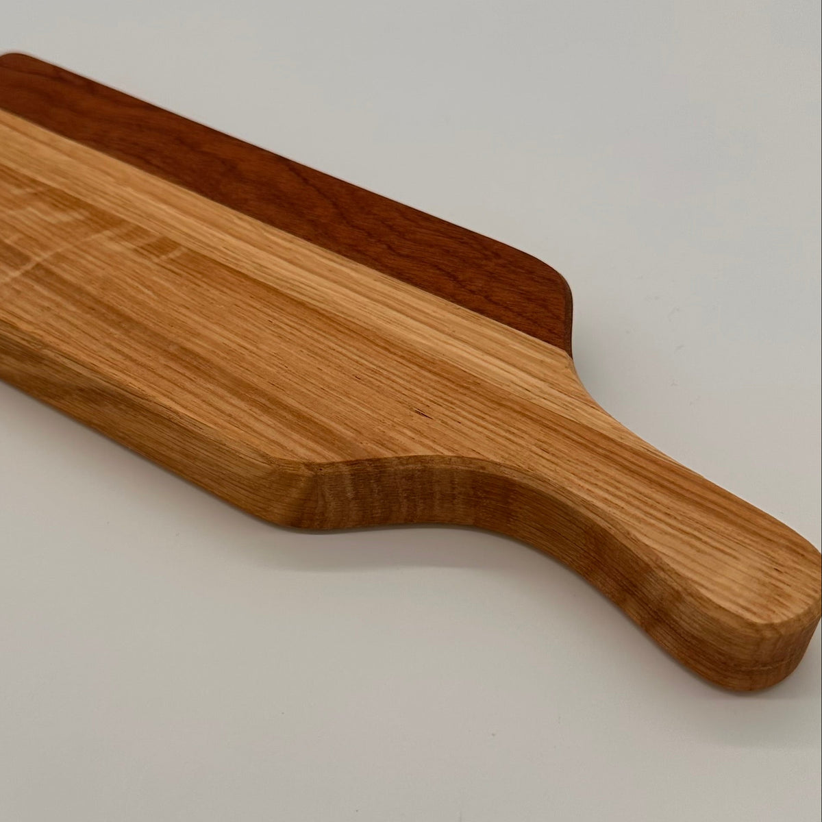 Wooden cutting board with a handle on a light gray background