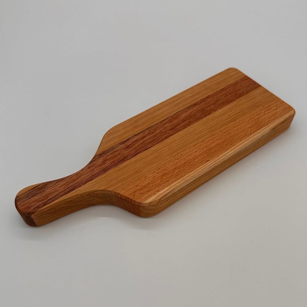 Wooden cutting board with a handle on a gray background