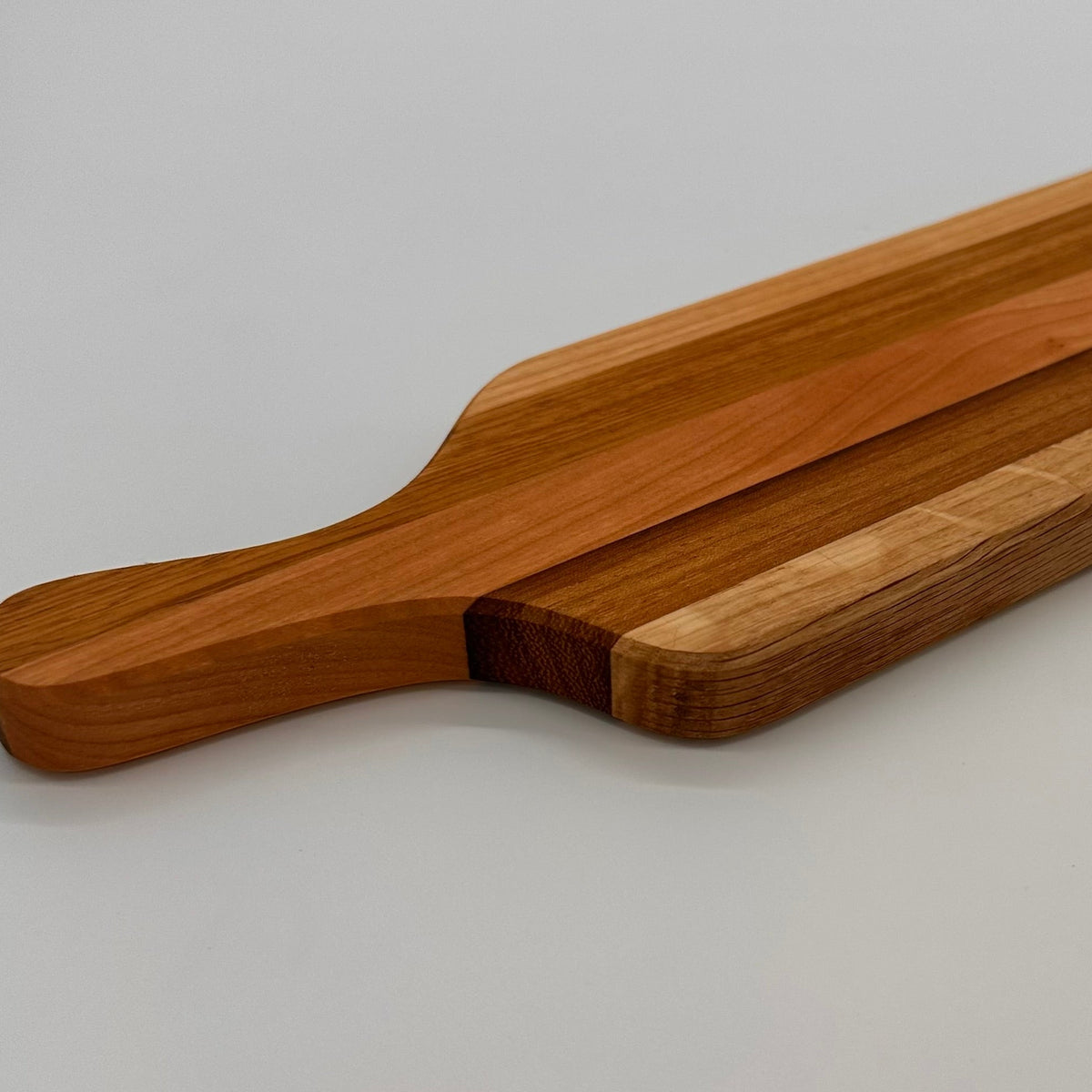 Wooden cutting board with a handle on a light gray background