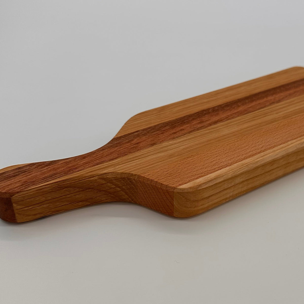 Wooden cutting board with a handle on a light gray background