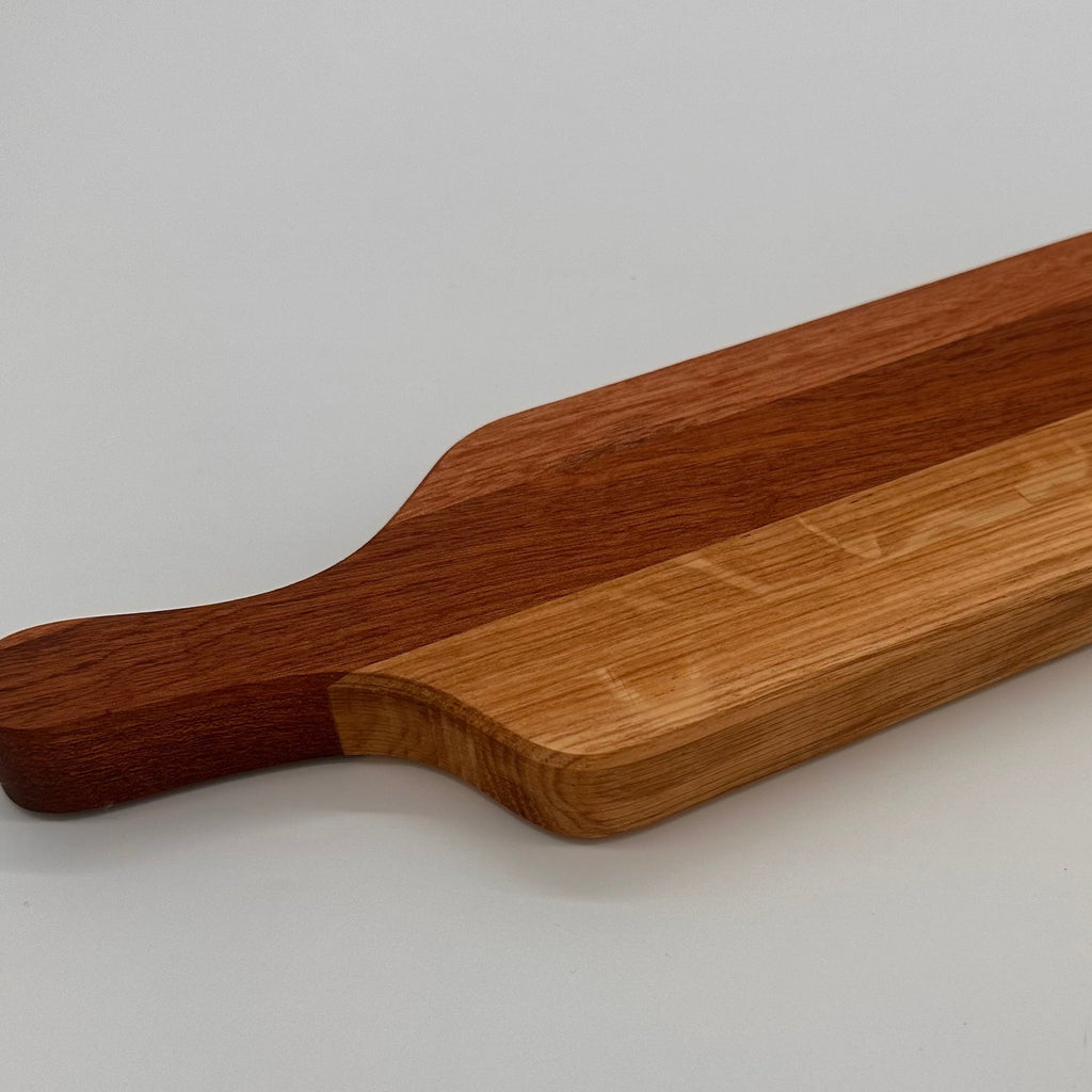 Wooden cutting board with a handle on a light gray background
