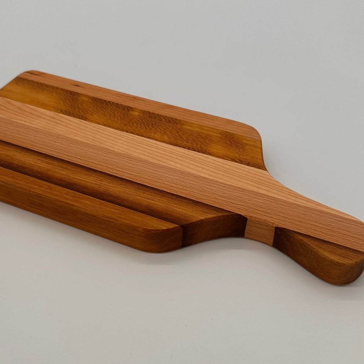 Wooden cutting board with a handle on a light gray background