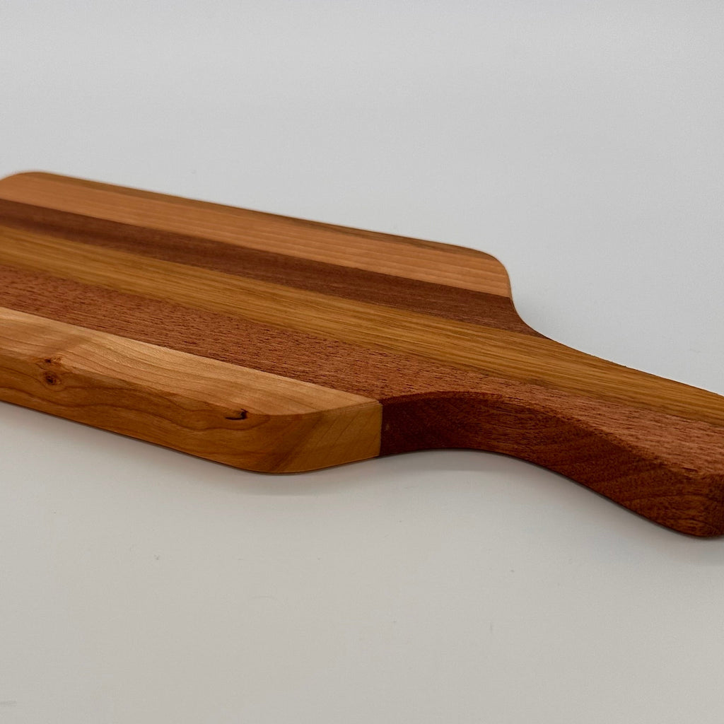 Wooden cutting board with a handle on a light gray background