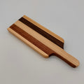 Wooden serving board with a handle on a light gray background