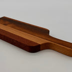 Wooden cutting board with a handle on a light gray background