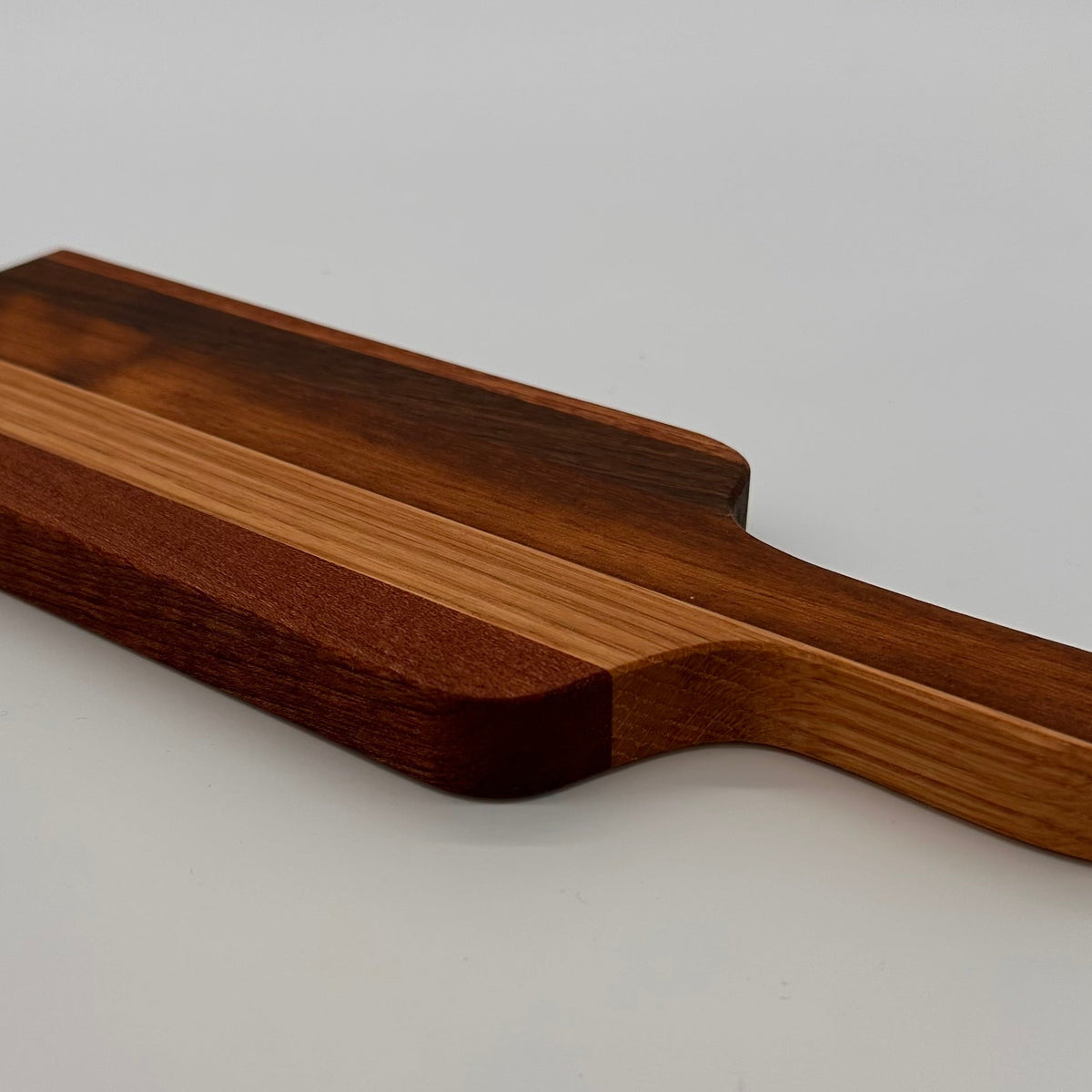 Wooden cutting board with a handle on a light gray background