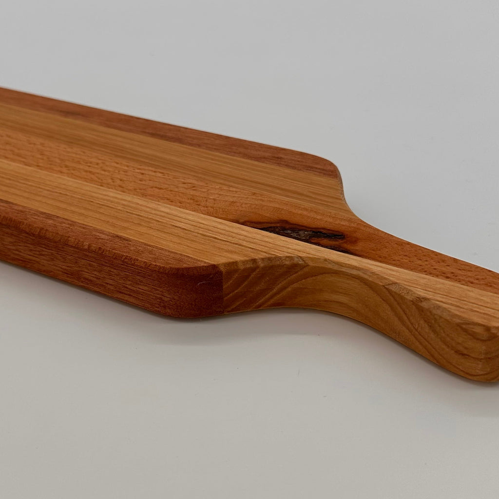 Wooden cutting board with handle on a light gray background
