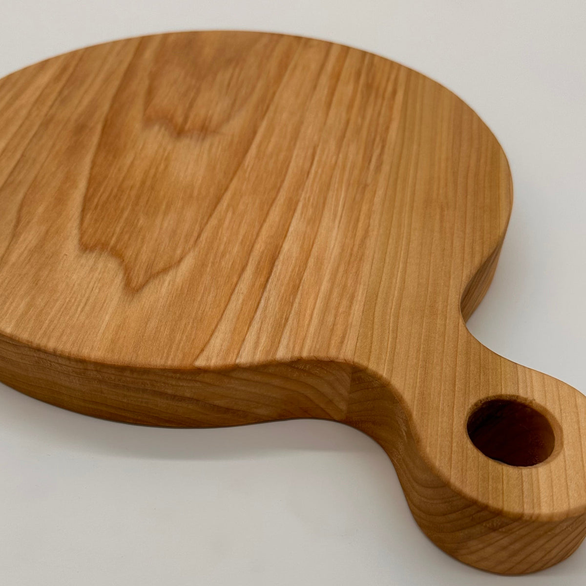 Wooden cutting board with handle on a light gray background