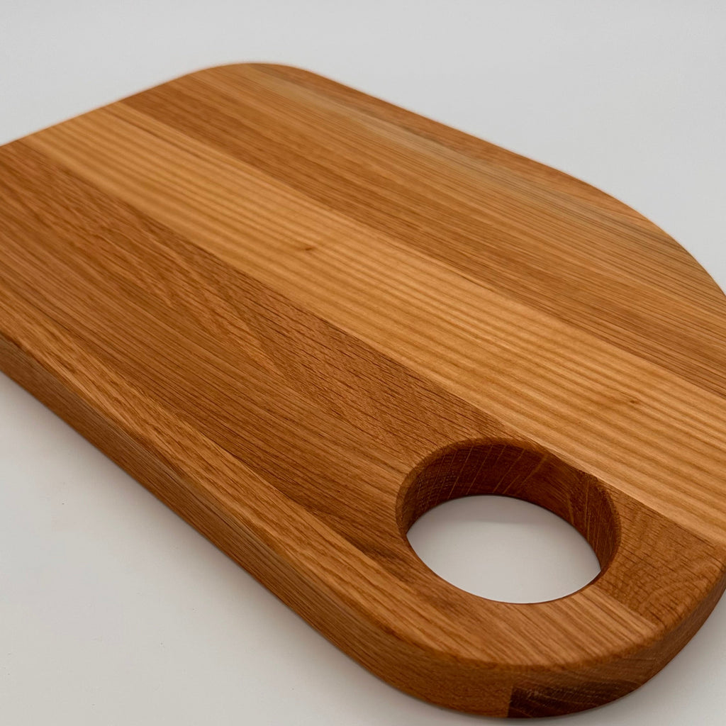 Wooden cutting board with a hole for hanging on a white background