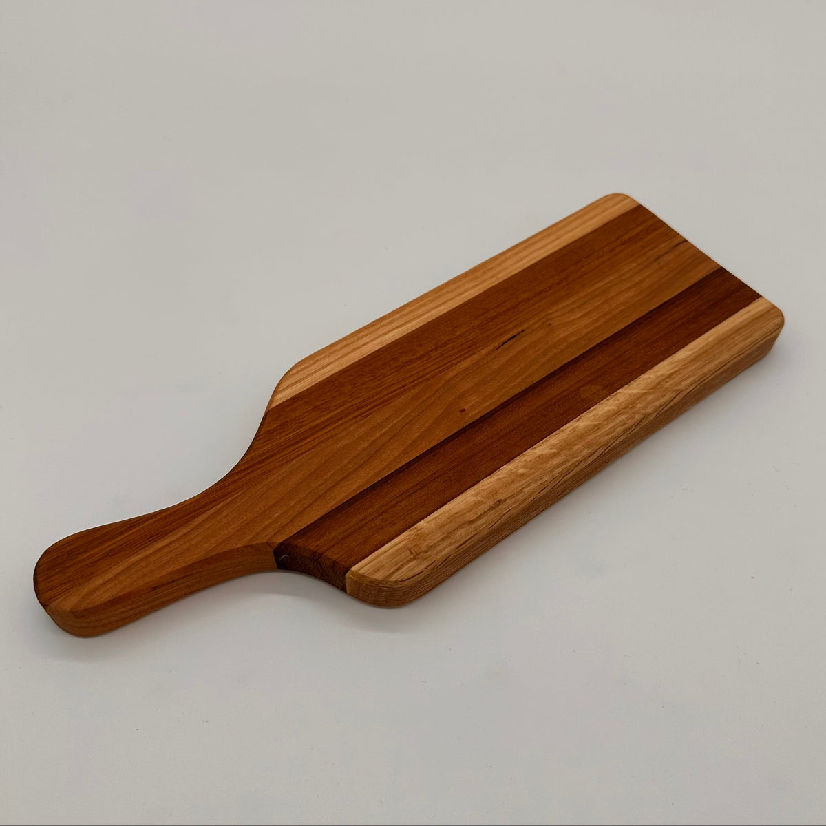 Wooden cutting board with a handle on a light gray background