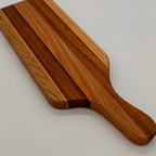 Wooden cutting board with a handle on a light gray background