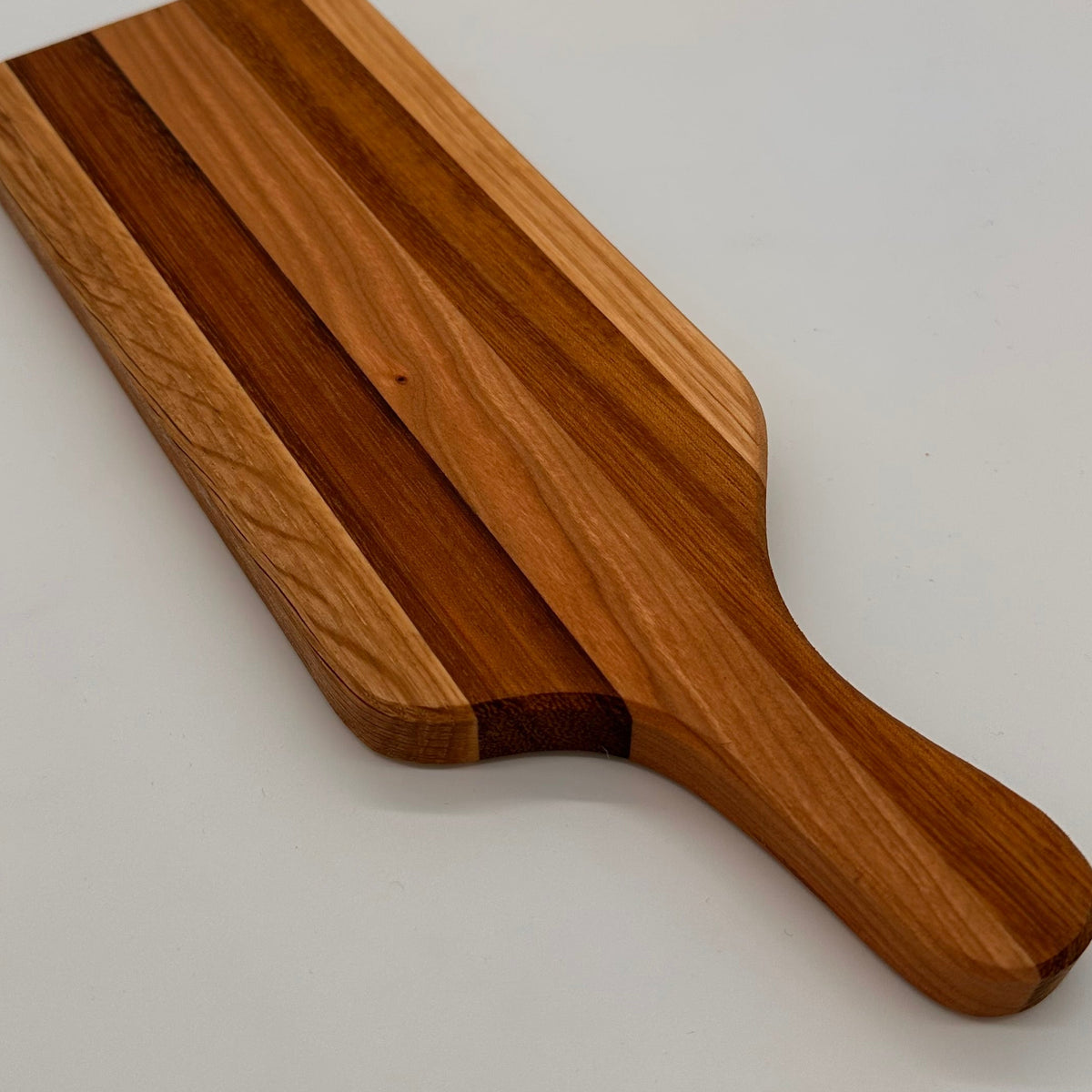 Wooden cutting board with a handle on a light gray background