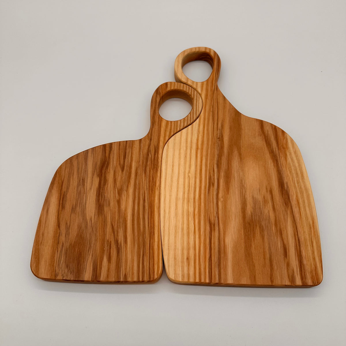Two wooden cutting boards with handles on a light gray background