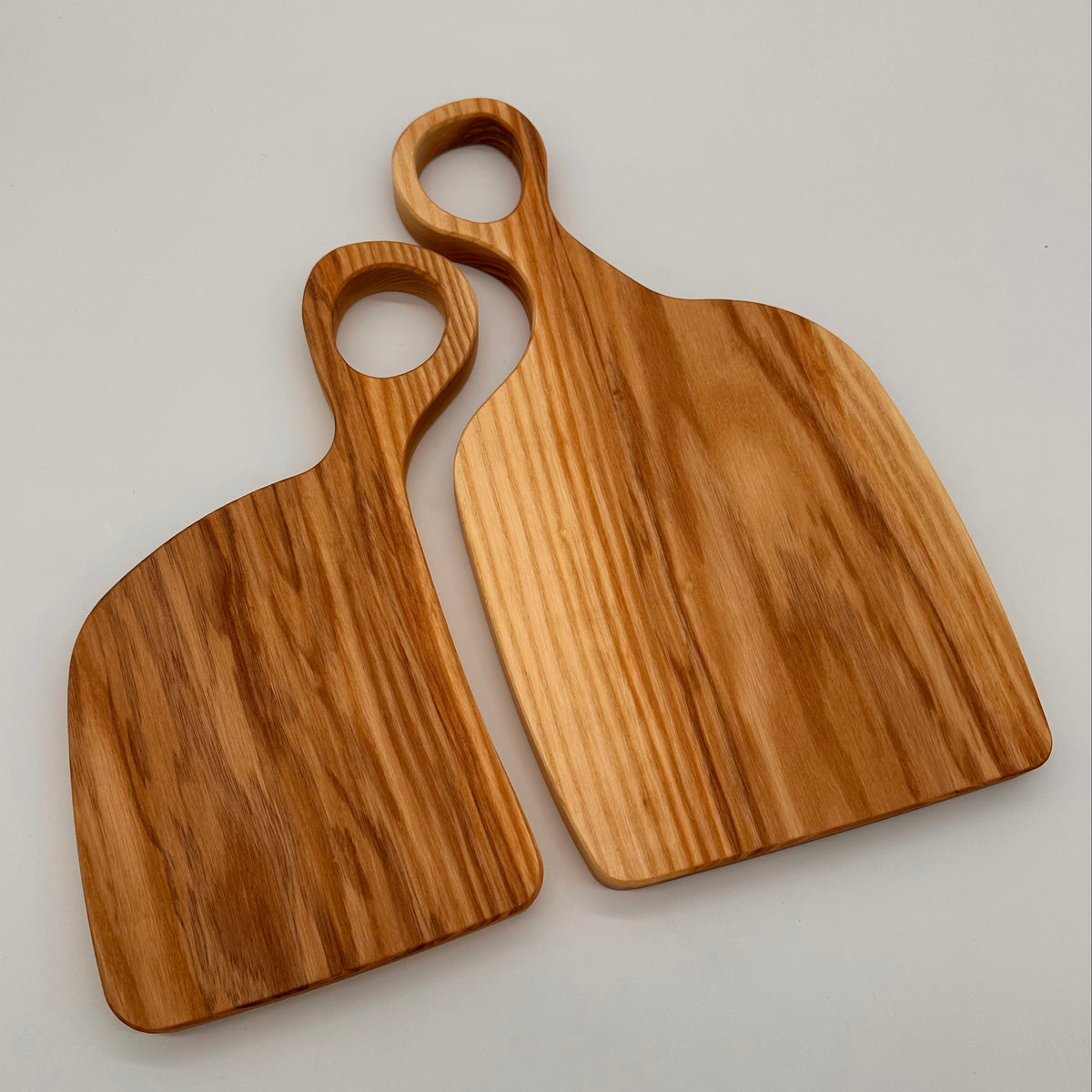 Two wooden cutting boards with handles on a light gray background