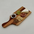 Wooden cutting board with cheese, crackers, grapes, and jam on a light gray background
