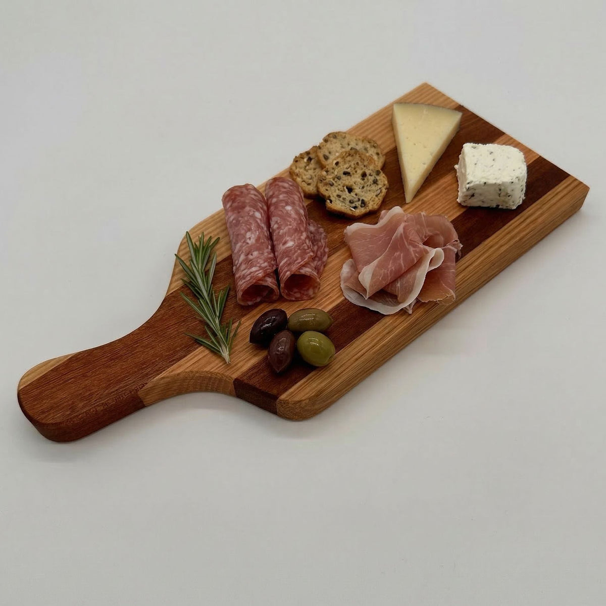 Wooden charcuterie board with cured meats, cheese, and olives on a white background