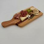 Wooden charcuterie board with cured meats, cheese, grapes, and crackers on a white background