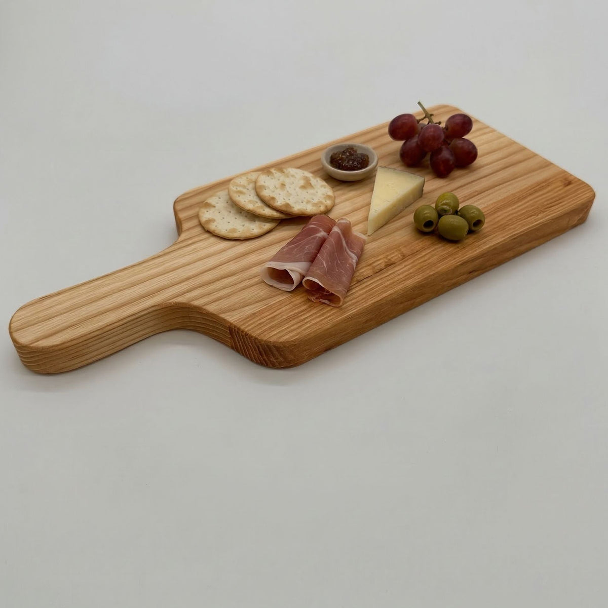 Wooden serving board with assorted food items on a light gray background