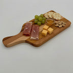 Wooden cutting board with cured meats, cheese, grapes, and nuts on a white background
