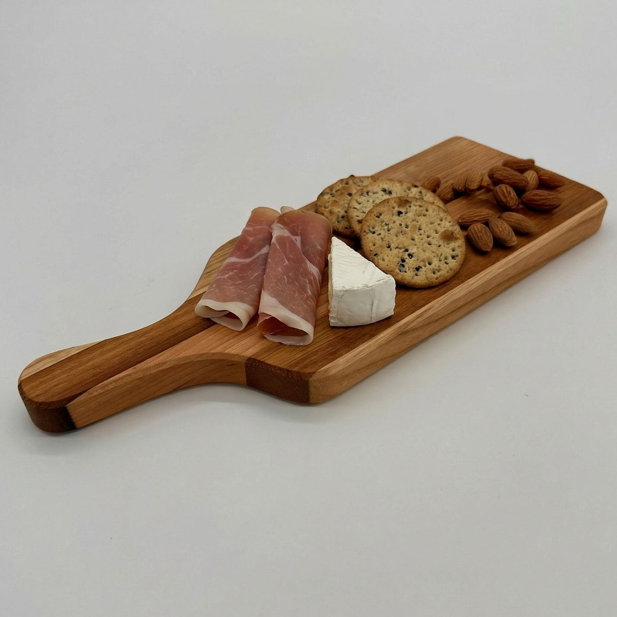 Wooden charcuterie board with cured meats, cheese, and crackers on a white background