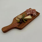 Wooden charcuterie board with cured meats, cheese, and olives on a light gray background