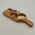 Wooden cutting board with assorted meats, cheeses, and crackers on a white background